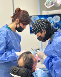 Two medical professionals in a surgical setting with a patient.